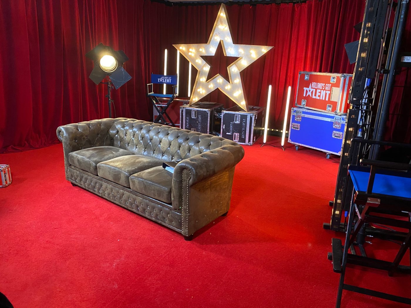 Decor van Holland's Got Talent met lichtster, rode gordijnen en bank