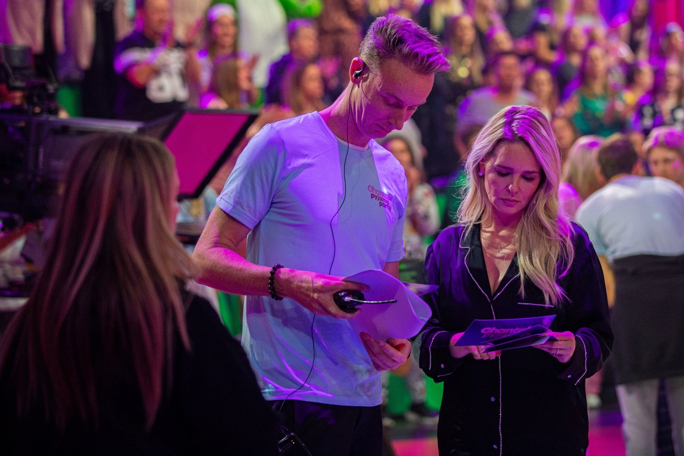 Chantal Janzen en een crewlid bespreken de kaartjes, met publiek op de achtergrond