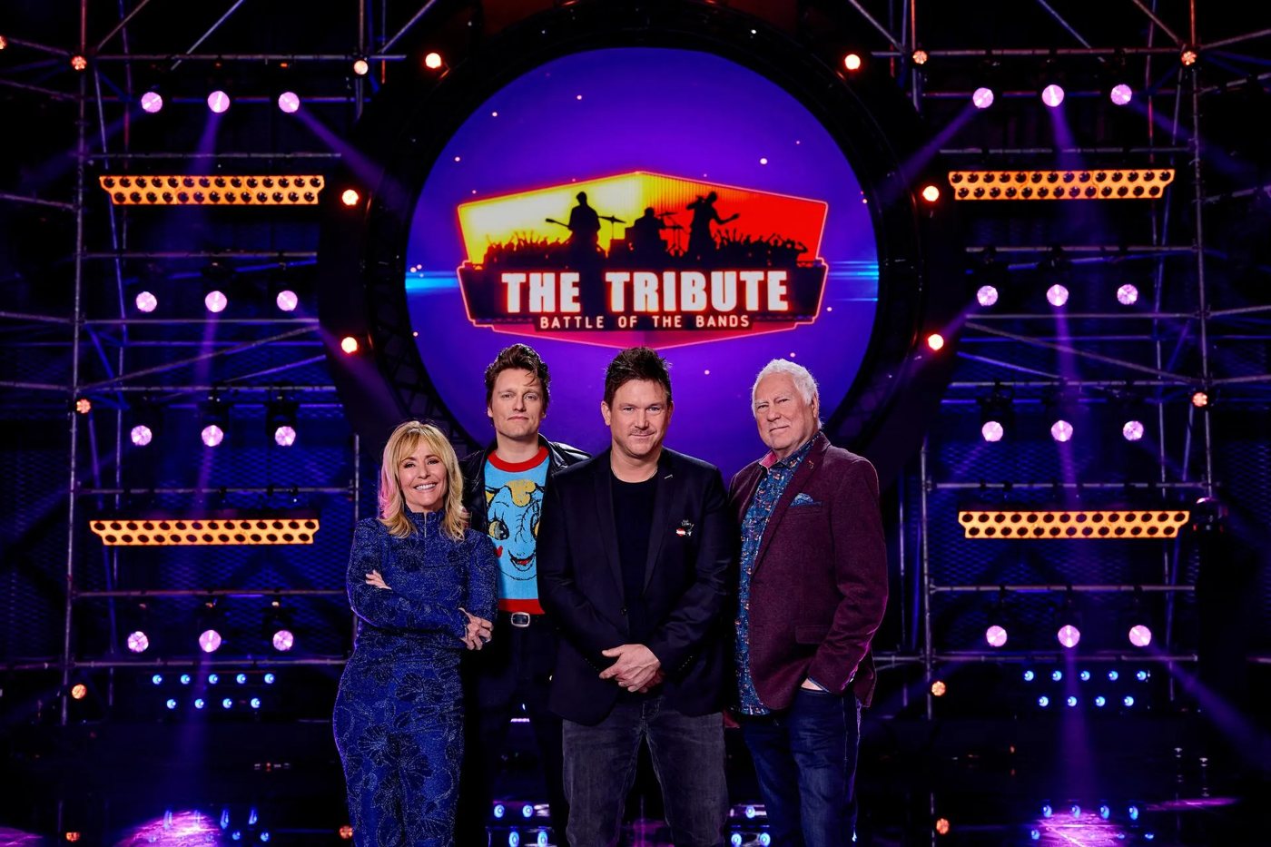 De jury van The Tribute – Battle of the Bands voor het decor met het logo