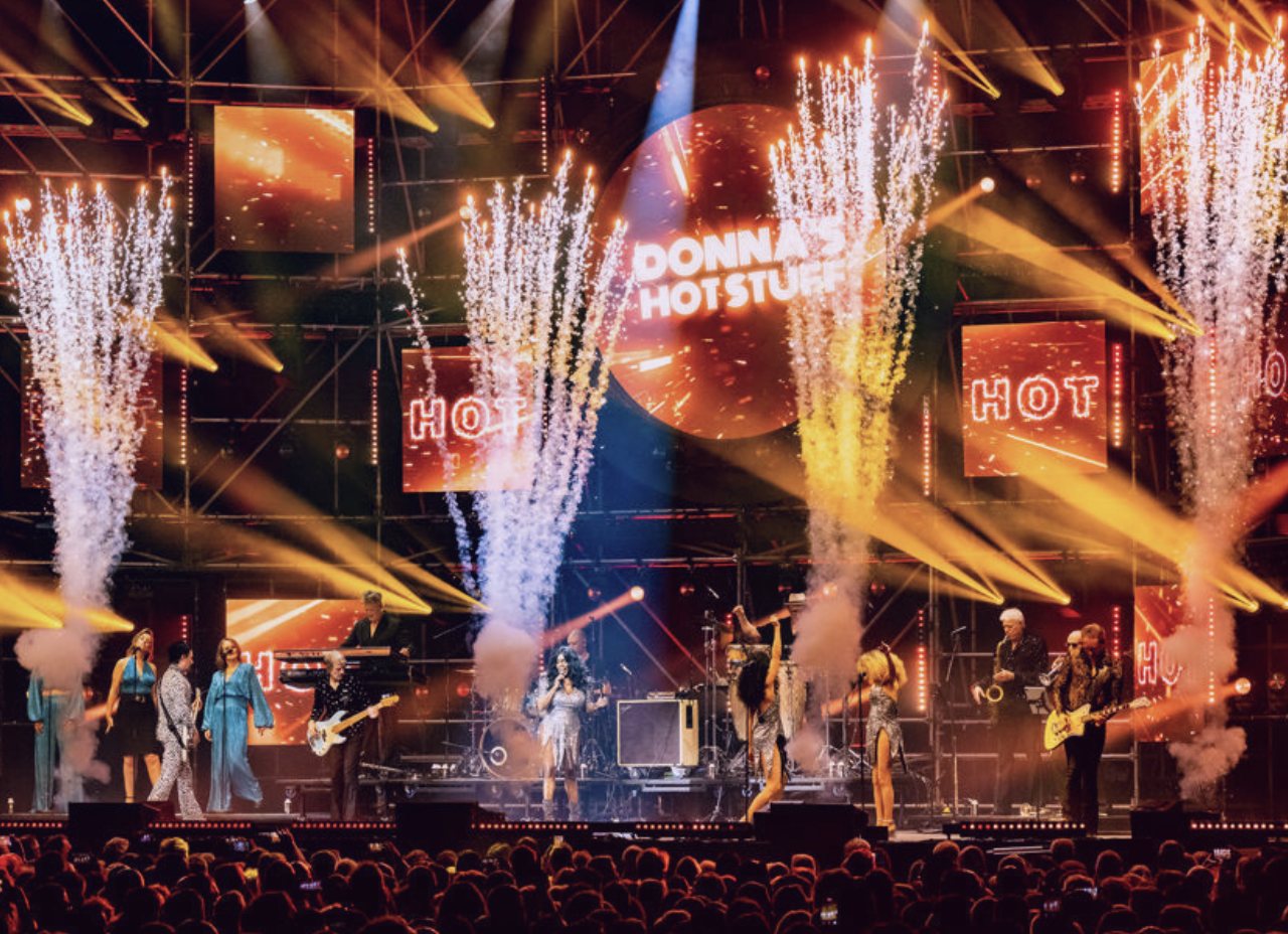 Groot podium met vuurfonteinen, een band en zangeressen